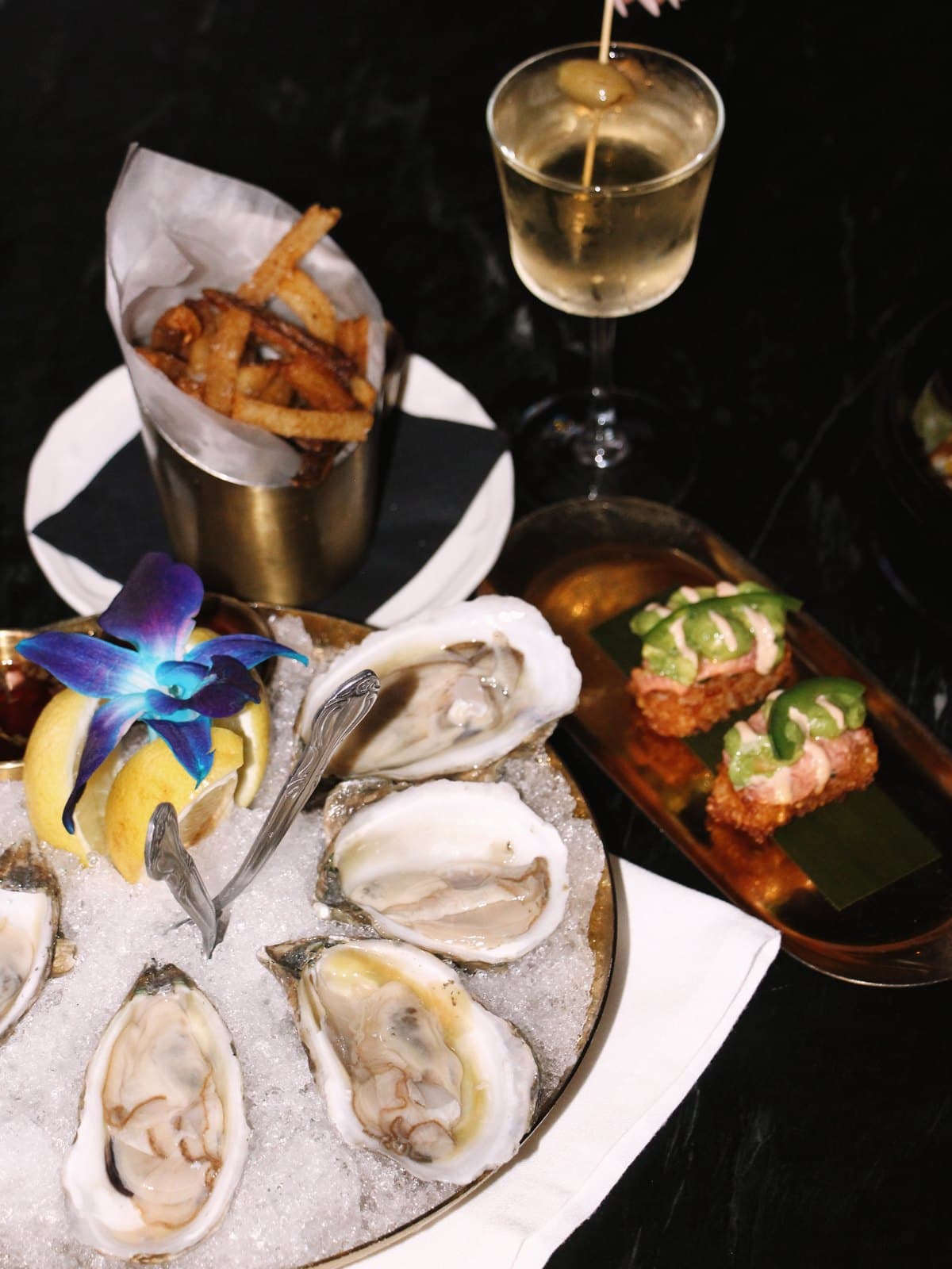 Dirty martini, truffle fries, spicy tuna crispy rice and oysters on ice on Jay's black marble bar