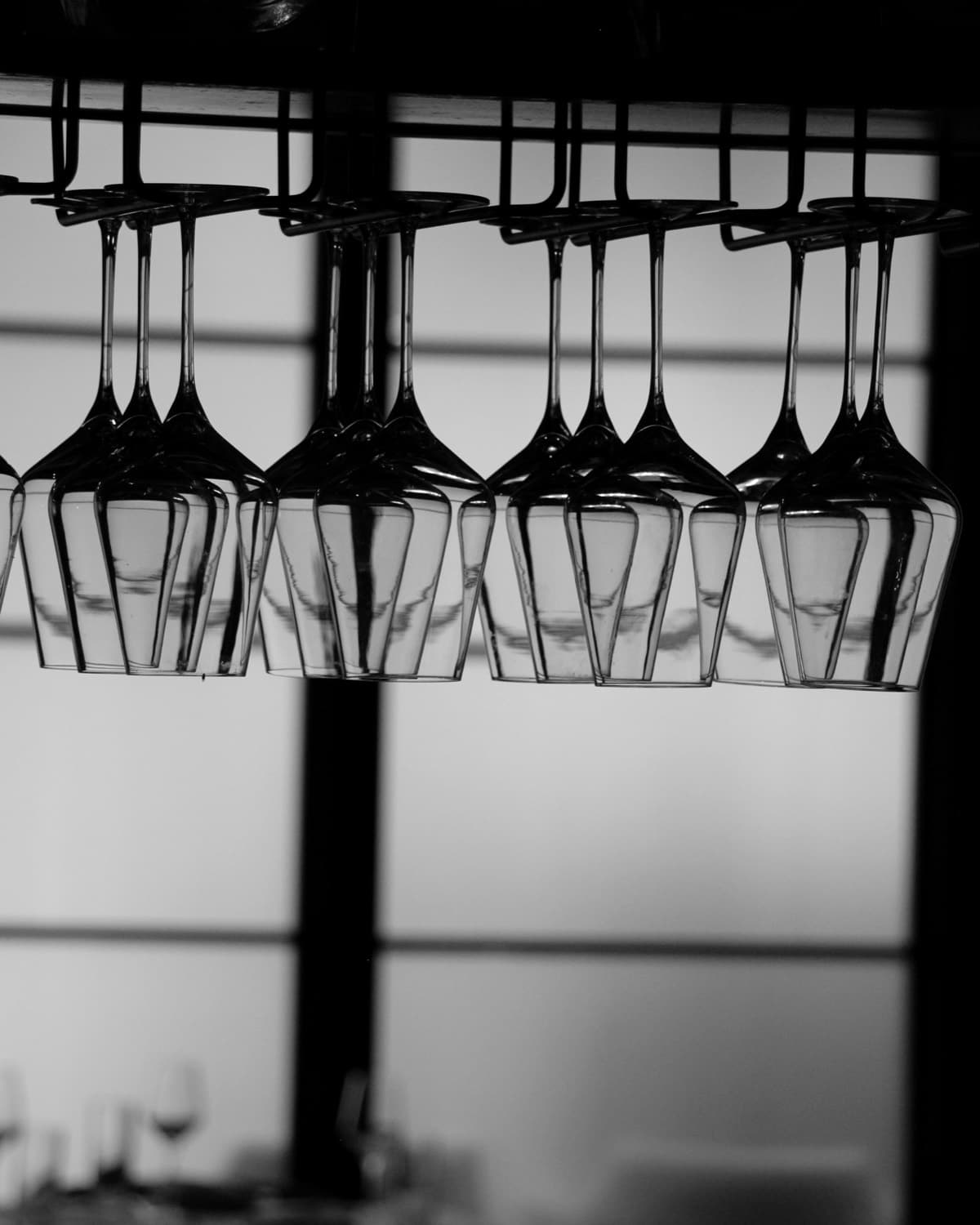 Wine glasses hanging upside down from a rack above Jay's bar