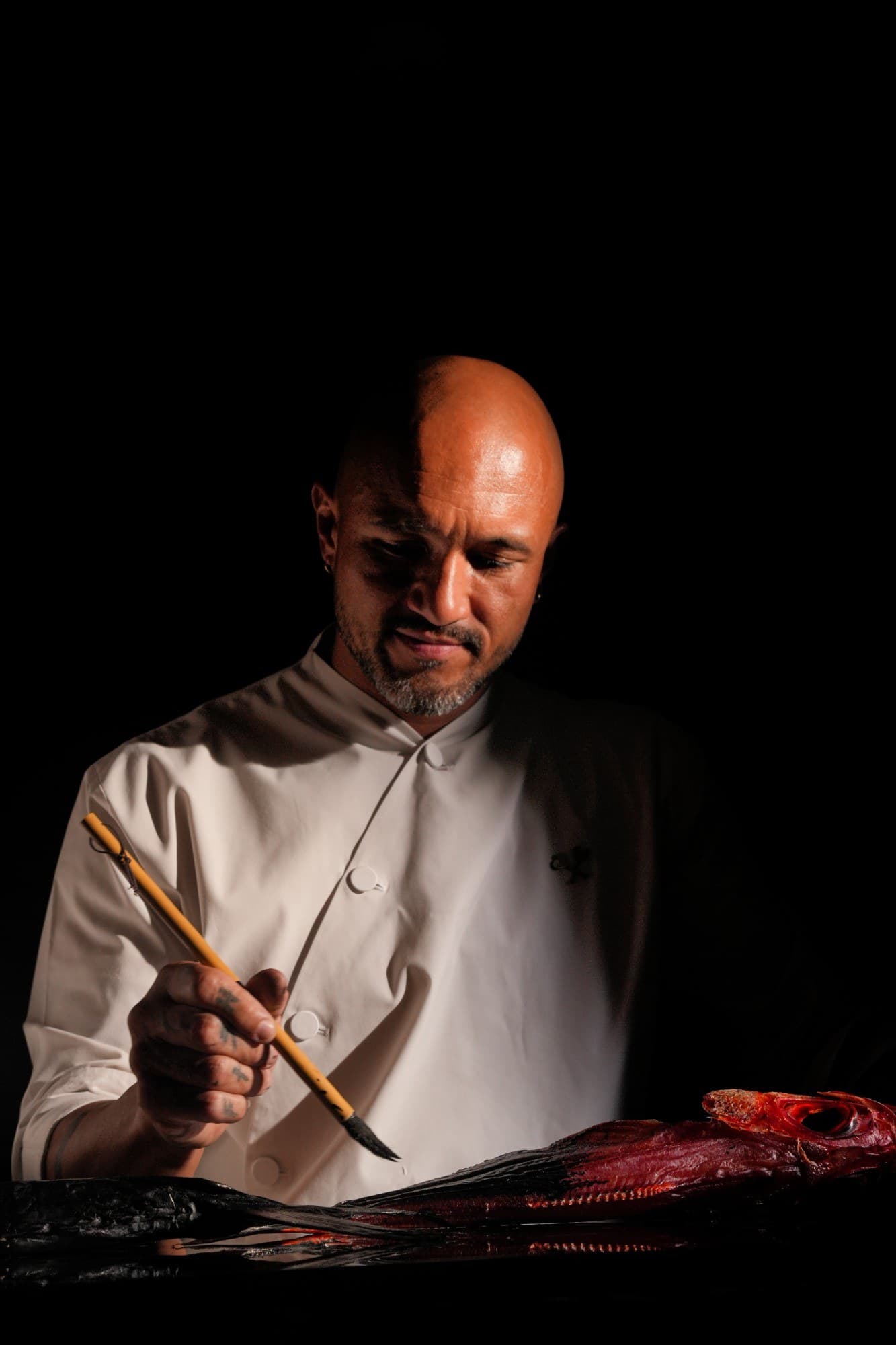 Chef Max Kamakura brushing nikiri over a whole fish